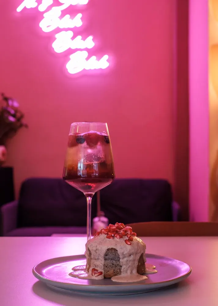 Postre y copa bajo el neón rosa del café