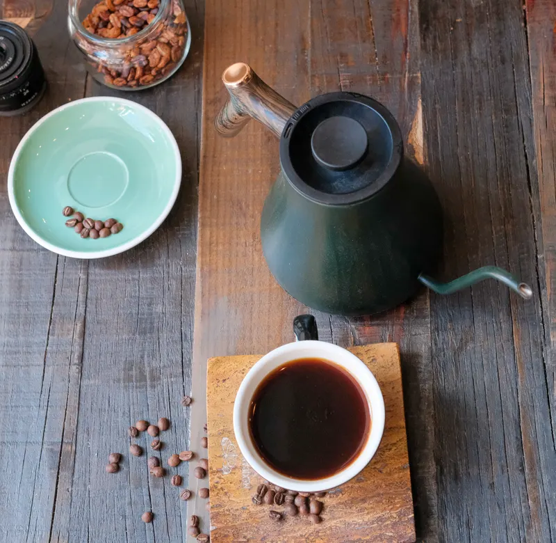 Teapot, coffee cup and beans on wood